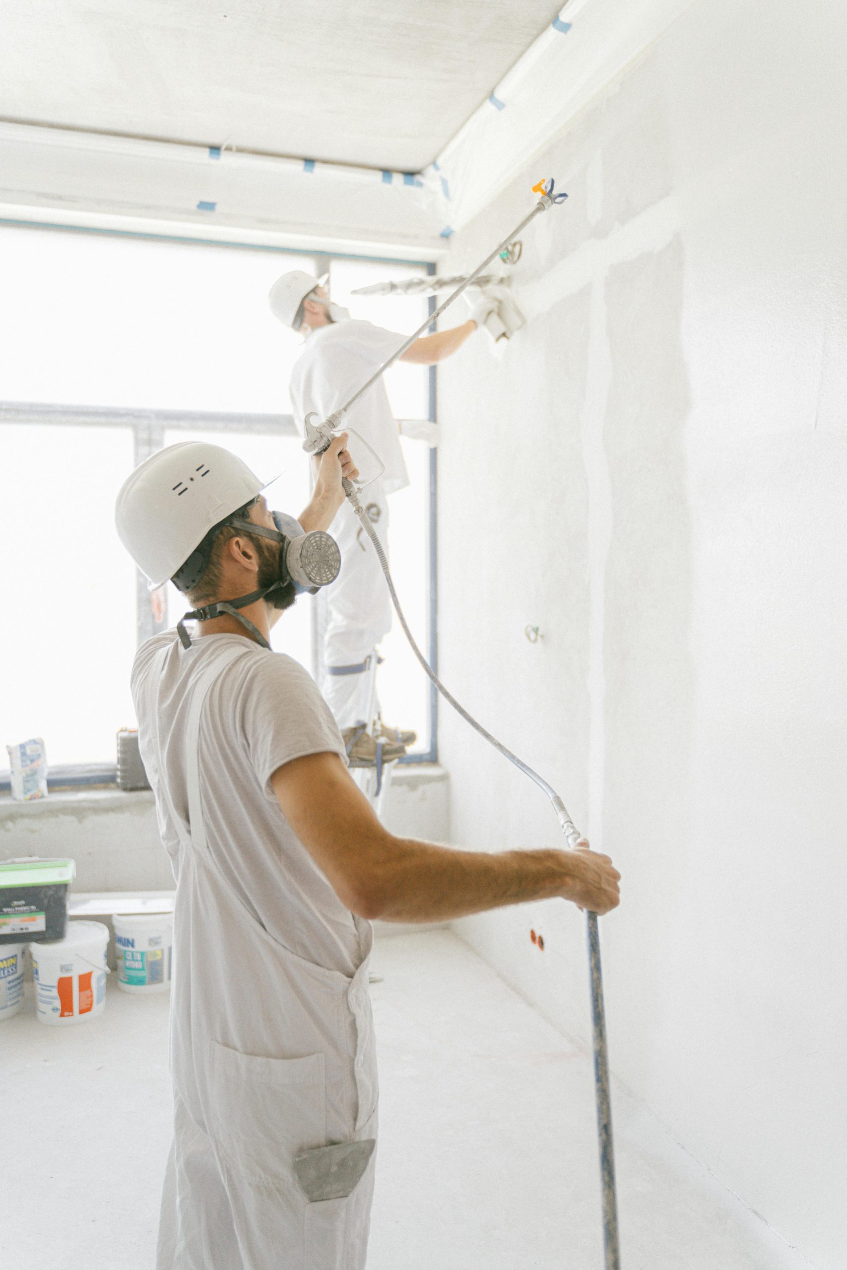 Two professional painters working indoors on wall renovation and painting project.